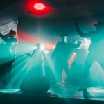 Dynamic concert scene with performers under vivid spotlights, creating an energetic atmosphere.